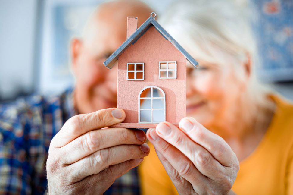 Man & woman holding a small wood house