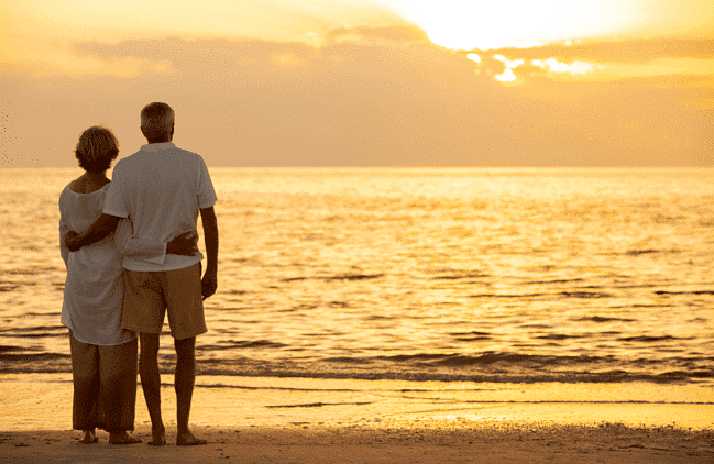 Man & woman standing on the beach at sunset