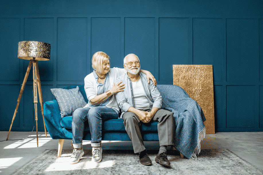 Man & woman sitting on blue couch smiling
