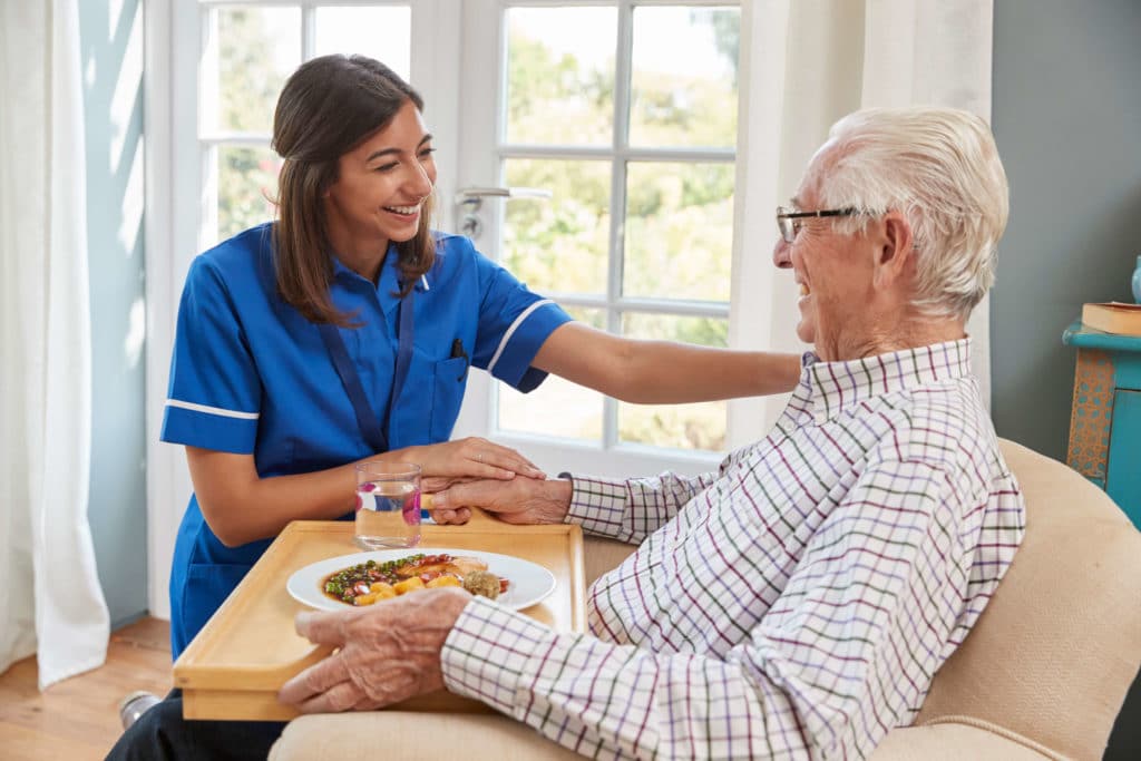 Caregiver assisting male resident with meal