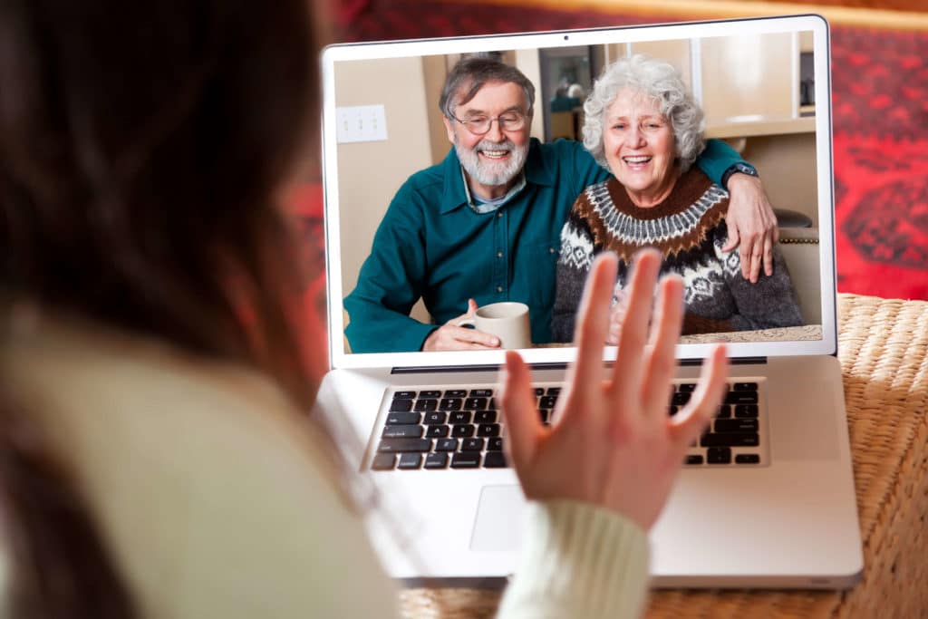 Woman & man sitting at table with coffee face timing on their computer