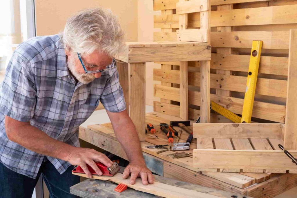 Man working in a woodshop sanding a piece of wood