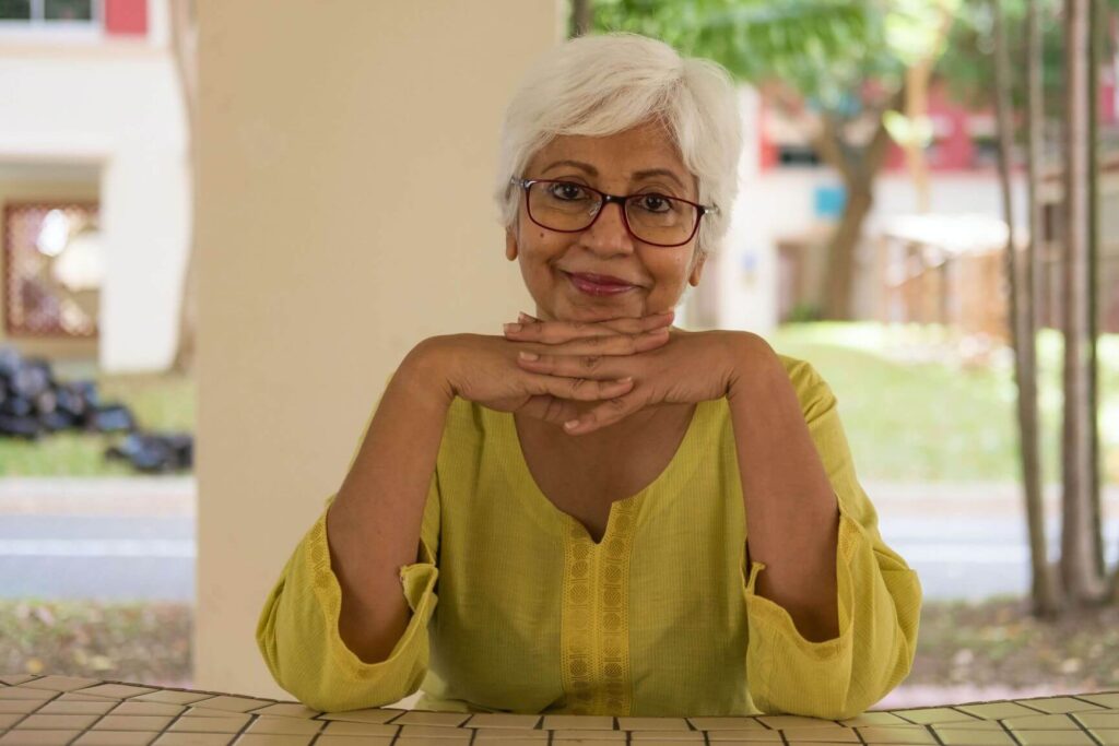 Women sitting in a chair with hands under her chin smiling