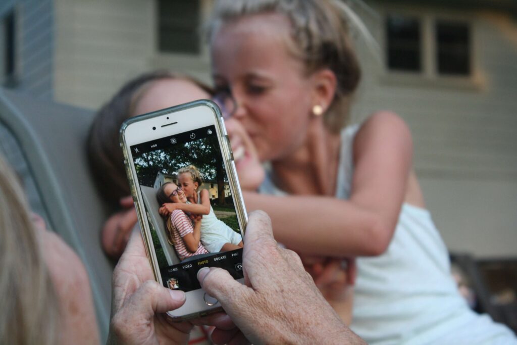 grandmother taking photo of granddaughters with smartphone