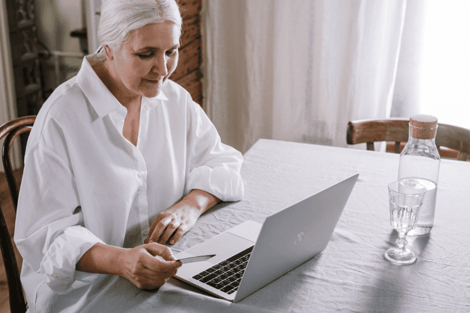 Woman sitting at table with water looking on her computer