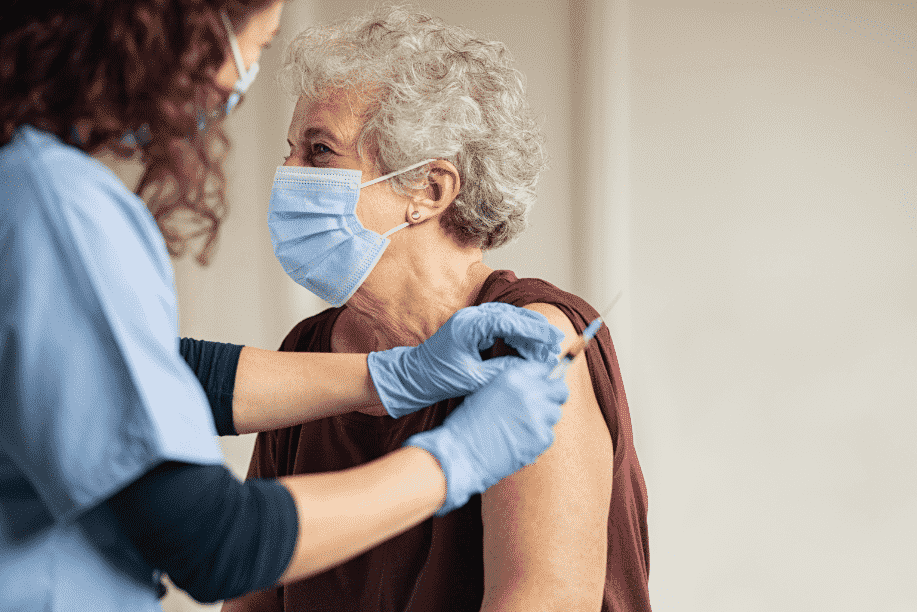 Woman sitting in a chair receiving a vaccine from a healthcare professional