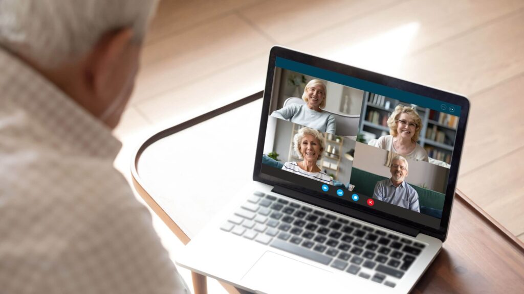 Man sitting at table with coffee face timing on his computer