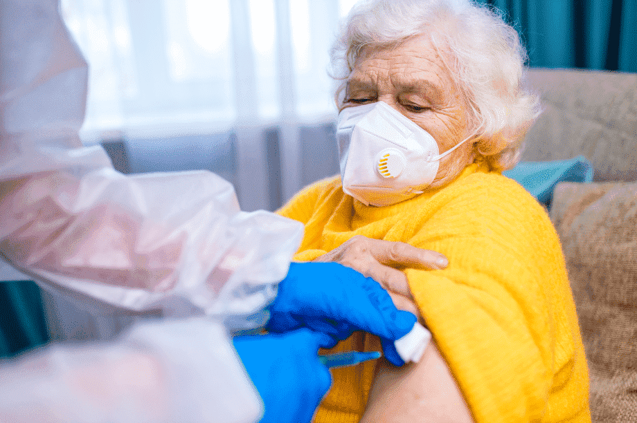 Woman sitting in a chair receiving a vaccine from a healthcare professional