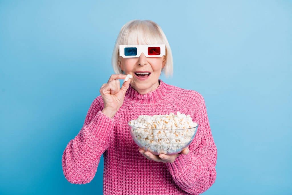 Woman with 3D glasses on and a bucket of popcorn