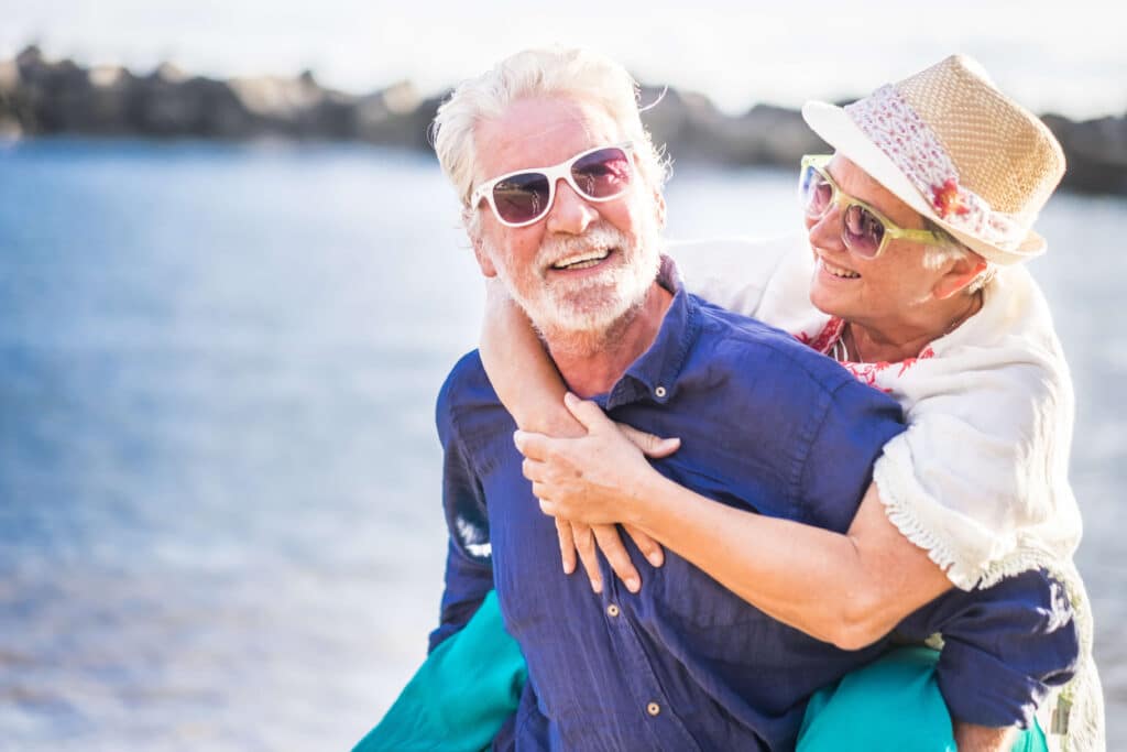 Man carrying a woman on his back on the beach