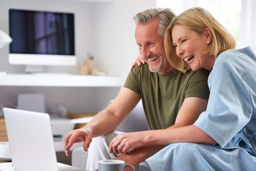 Man & woman sitting in front of computer smiling