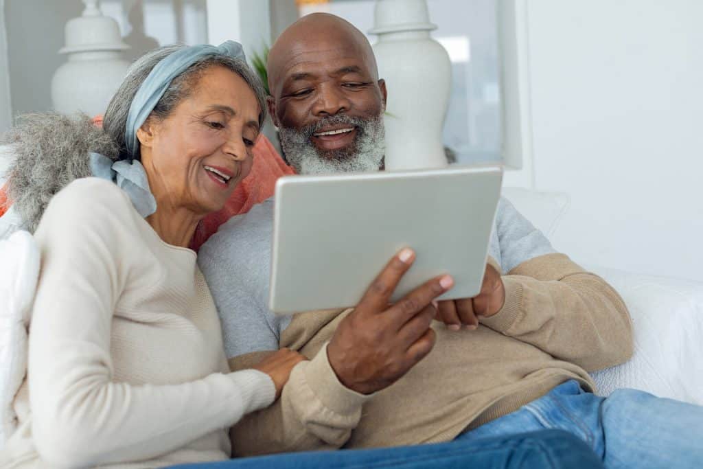 Man & Woman sitting on the couch searching on their tablet