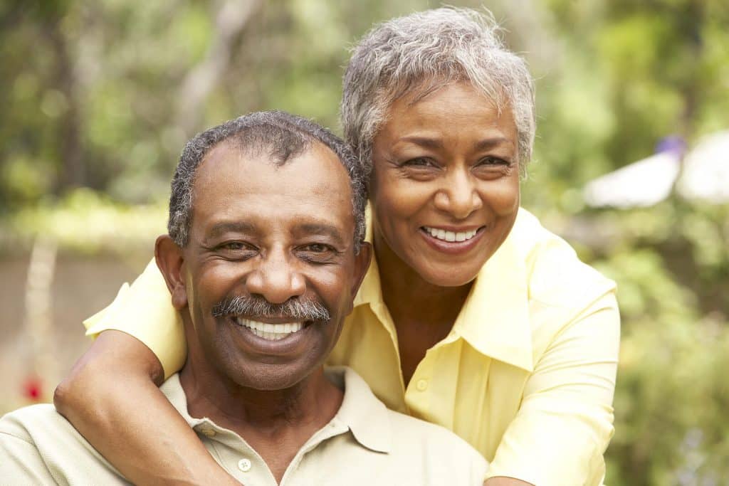 Man sitting in chair with woman hugging him from the back