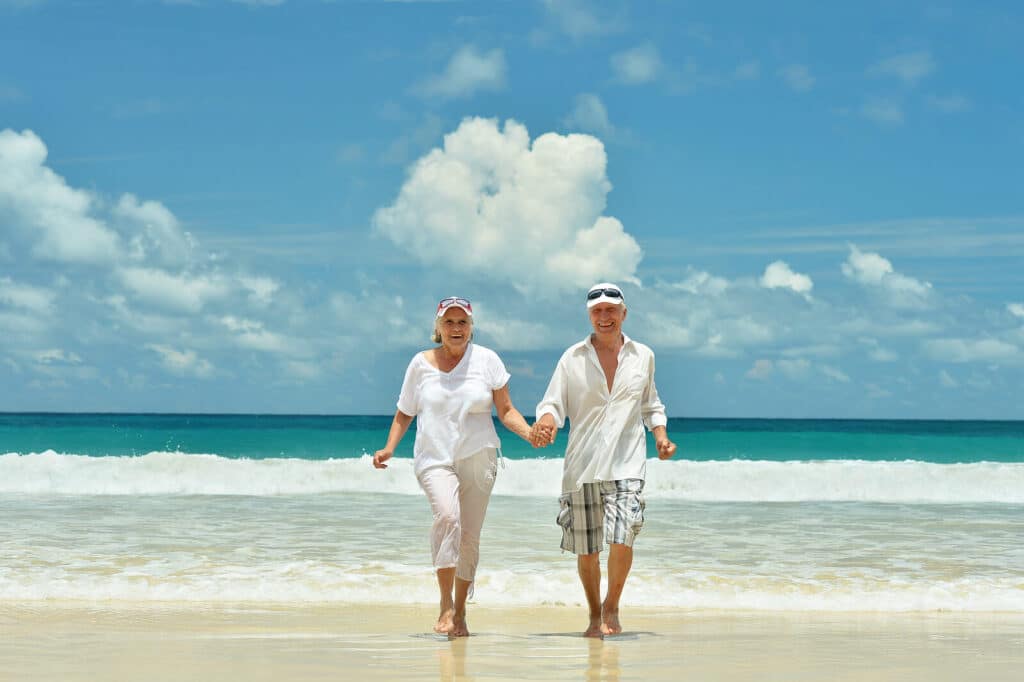 Man & woman holding hands on the beach as the tide comes in