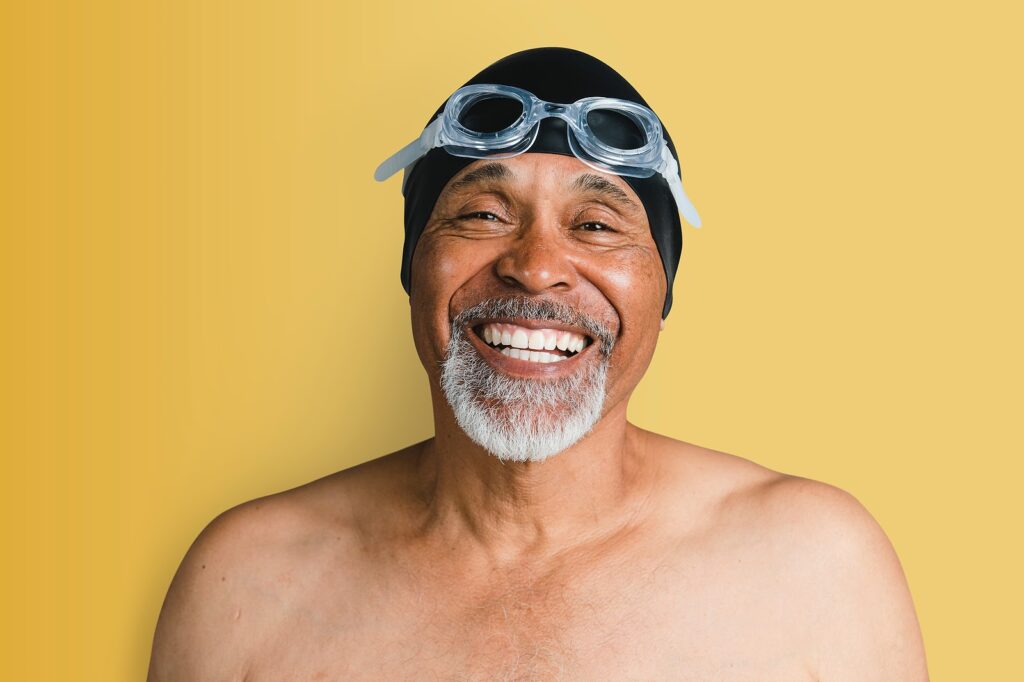 Man with swimming cap & goggles smiling