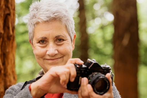 Woman holding a camera outdoors on an autumn day taking pictures