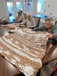 Photo of four women sitting at a table knitting