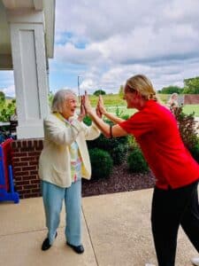 Senior woman and caregiver high-fiving