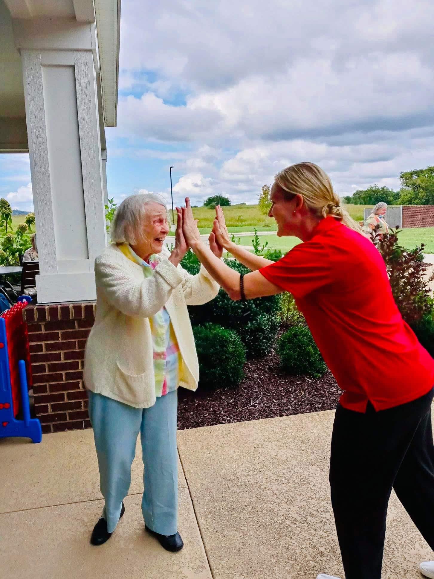 Senior woman and caregiver high-fiving