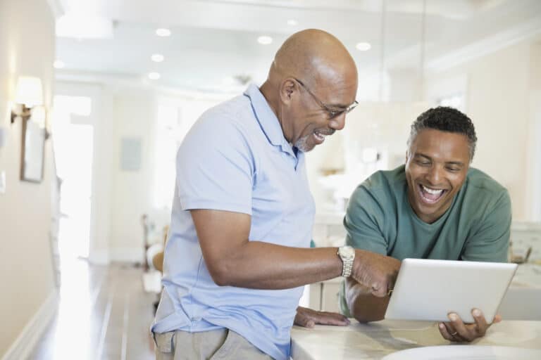 Two people laughing, looking at a tablet