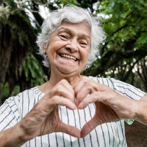 Photo of woman smiling making a heart shape with her hands