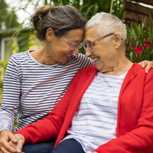 Photo of two women giving a friendly embrace, holding hands and smiling