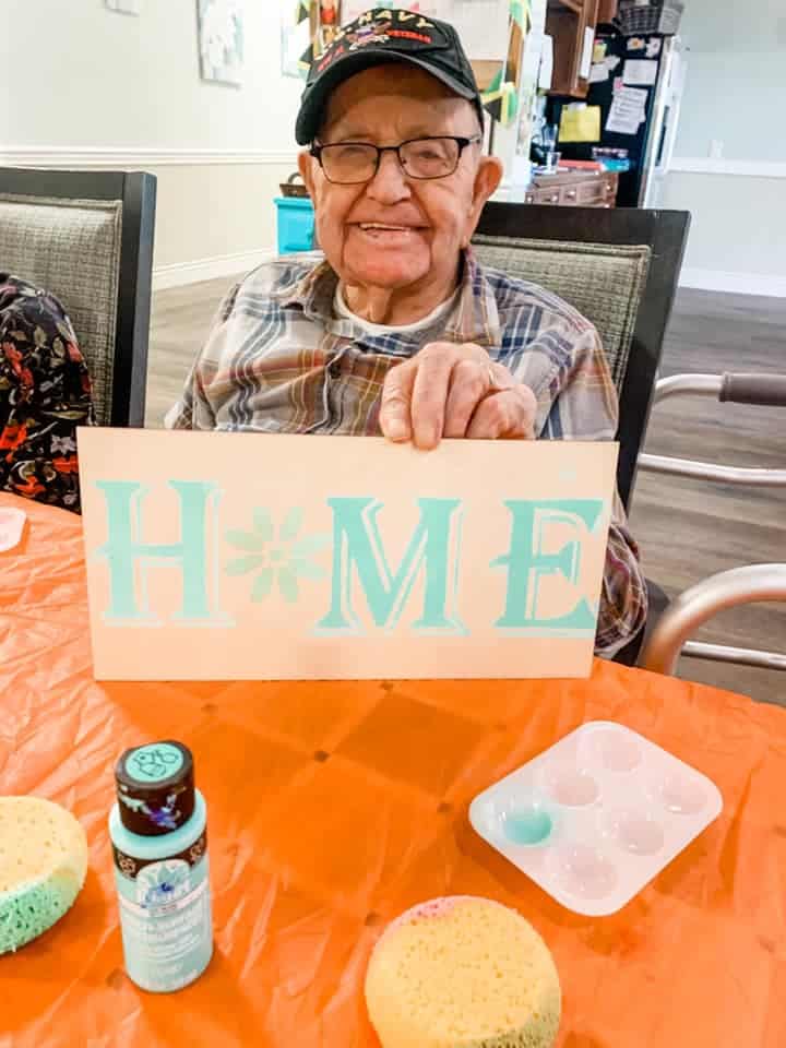 Man sitting at table with a painted Photo the says home