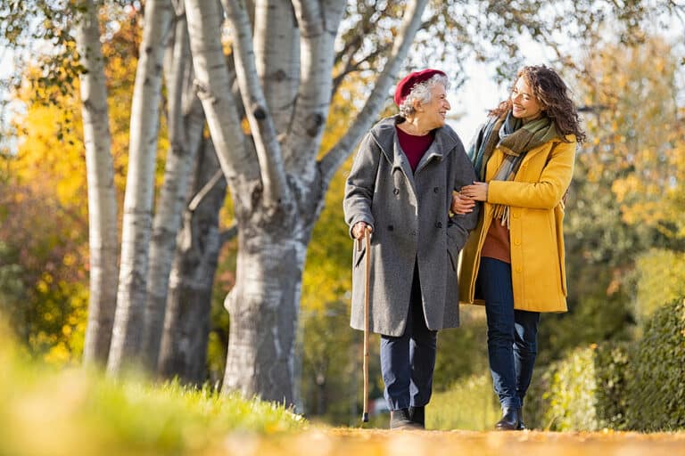 A senior mother with her daughter walking outside during the fall