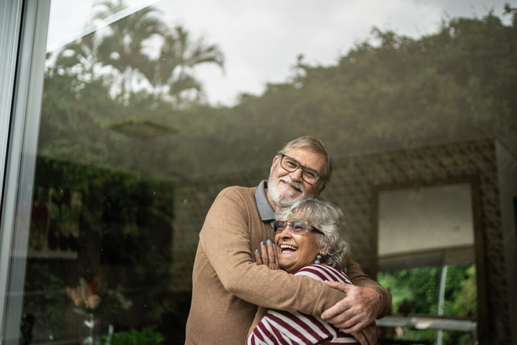 Contemplative senior couple looking though window at home