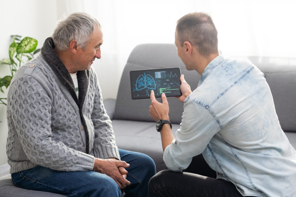 Senior man with loved one reviewing AI monitoring system for health updates