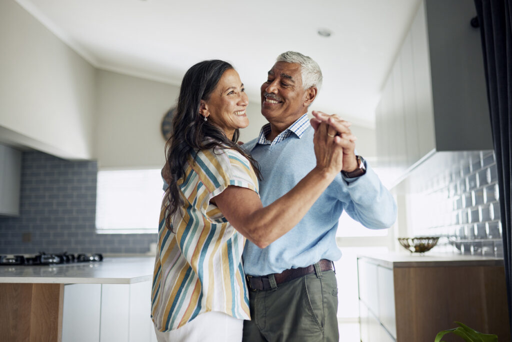 An older man and woman dancing together in their kitchen